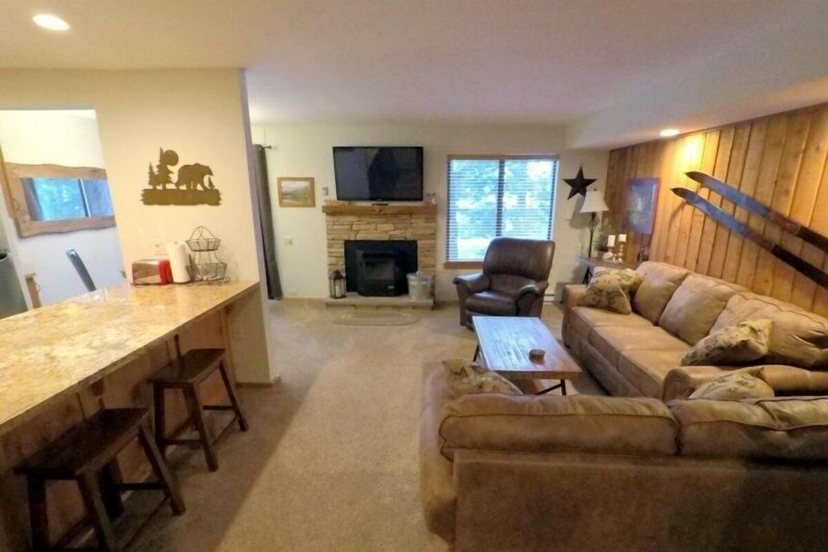Una sala de estar con chimenea, televisor, sofá y comedor con sillas.