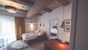 A modern bedroom with a wooden ceiling, a bed with white bedding, a wooden dining table, and a small rug. - Luis Stadl (Regensburg)
