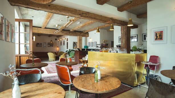 A cozy restaurant with wooden tables and chairs, a bar area, and a rustic ceiling. - Luis Stadl (Regensburg)