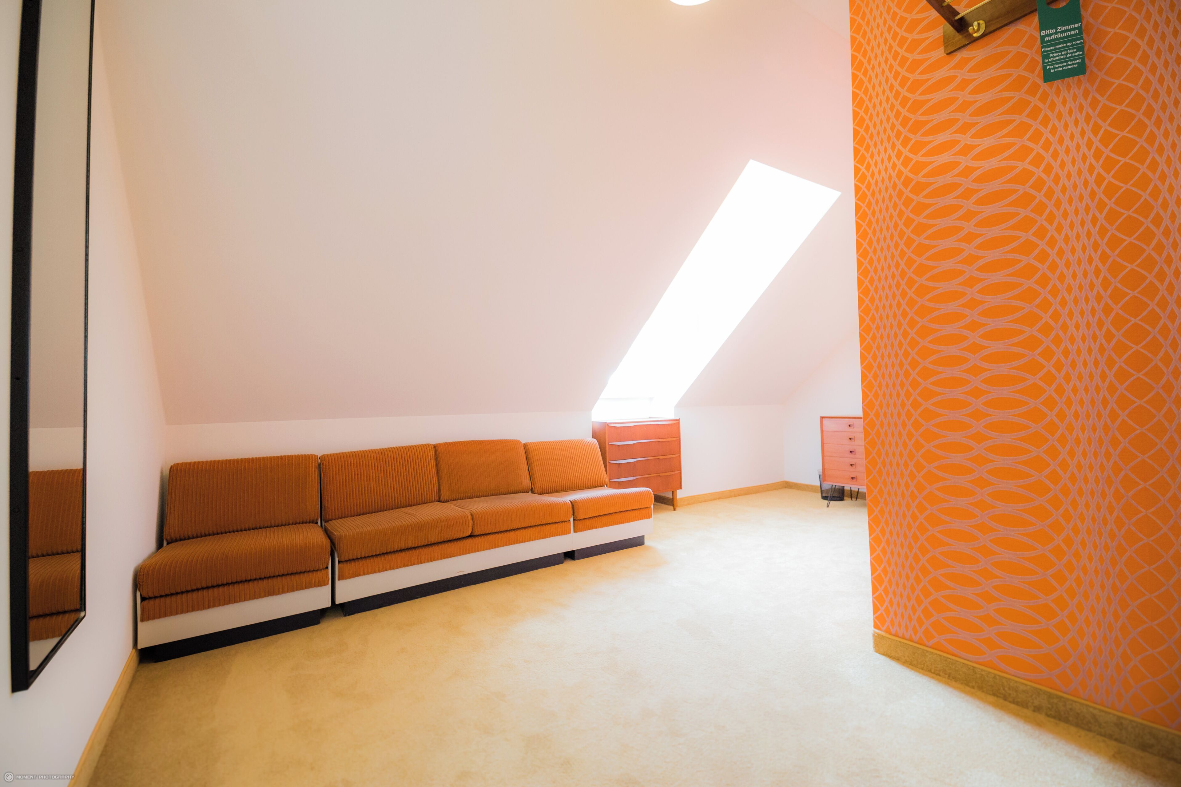 Una habitación con un sofá, un aparador y un papel tapiz estampado.