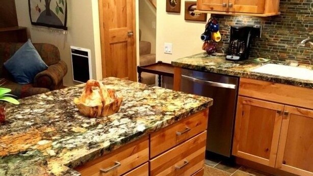A kitchen with a granite countertop, wooden cabinets, and a tiled floor. - 114 Premium Condo (Mammoth Lakes)
