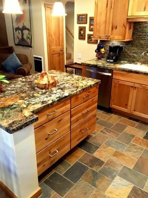 A kitchen with a granite countertop, wooden cabinets, and a tiled floor. - 114 Premium Condo (Mammoth Lakes)