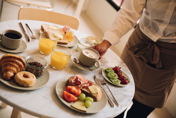 Uma mesa de café da manhã com croissants, torradas, frutas e bebidas.