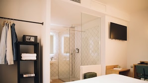 A hotel room with a bed, a bedside table, a TV, a shower area, and a wardrobe. - H La Paloma Boutique (Barcelona)