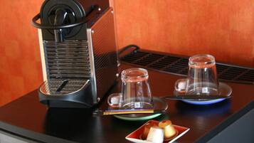 Une machine à café est posée sur une table, à côté de deux tasses et d’une assiette de viennoiseries.