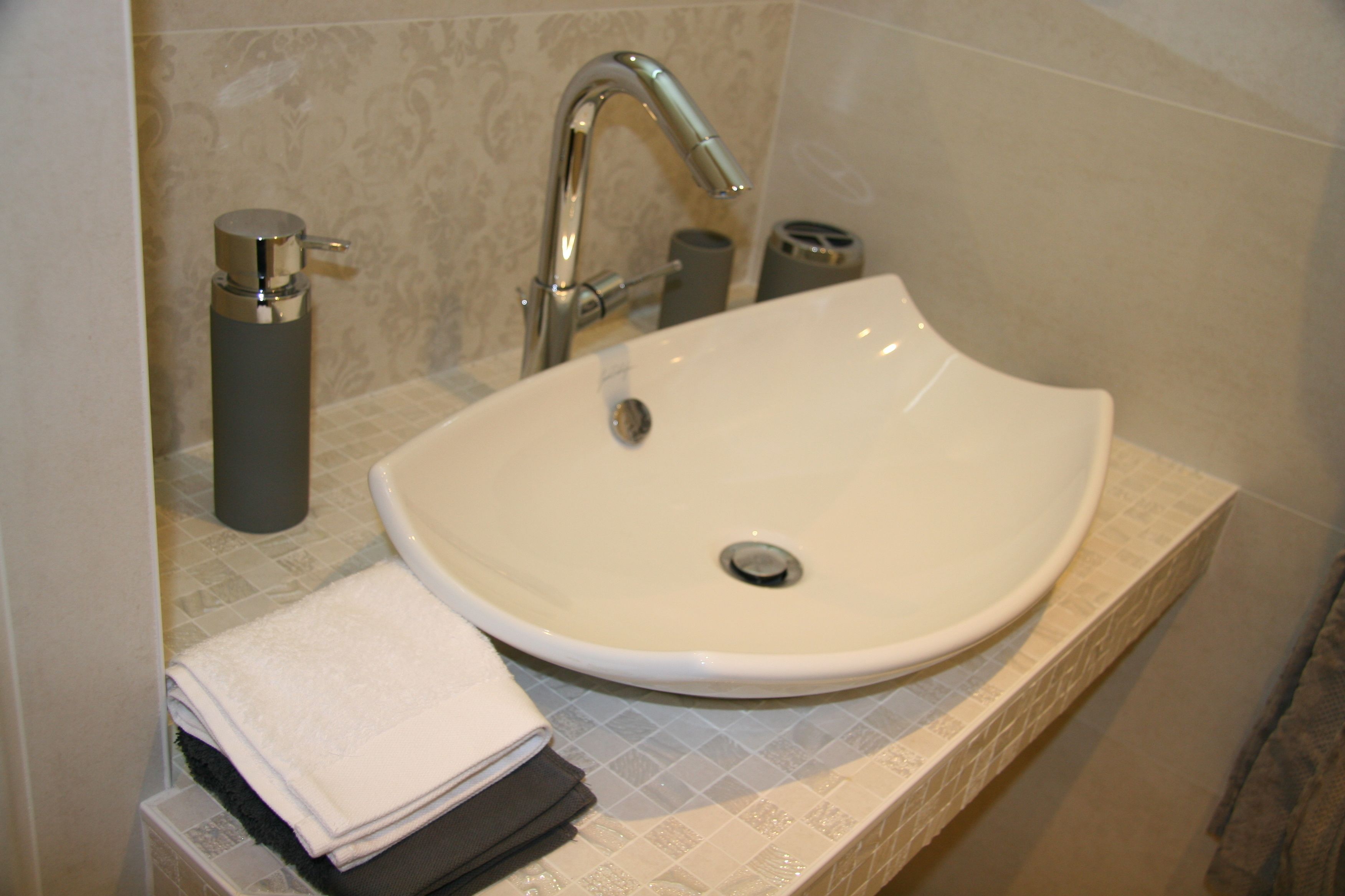 Un baño con un lavamanos blanco, un grifo moderno y un perchero para toallas.