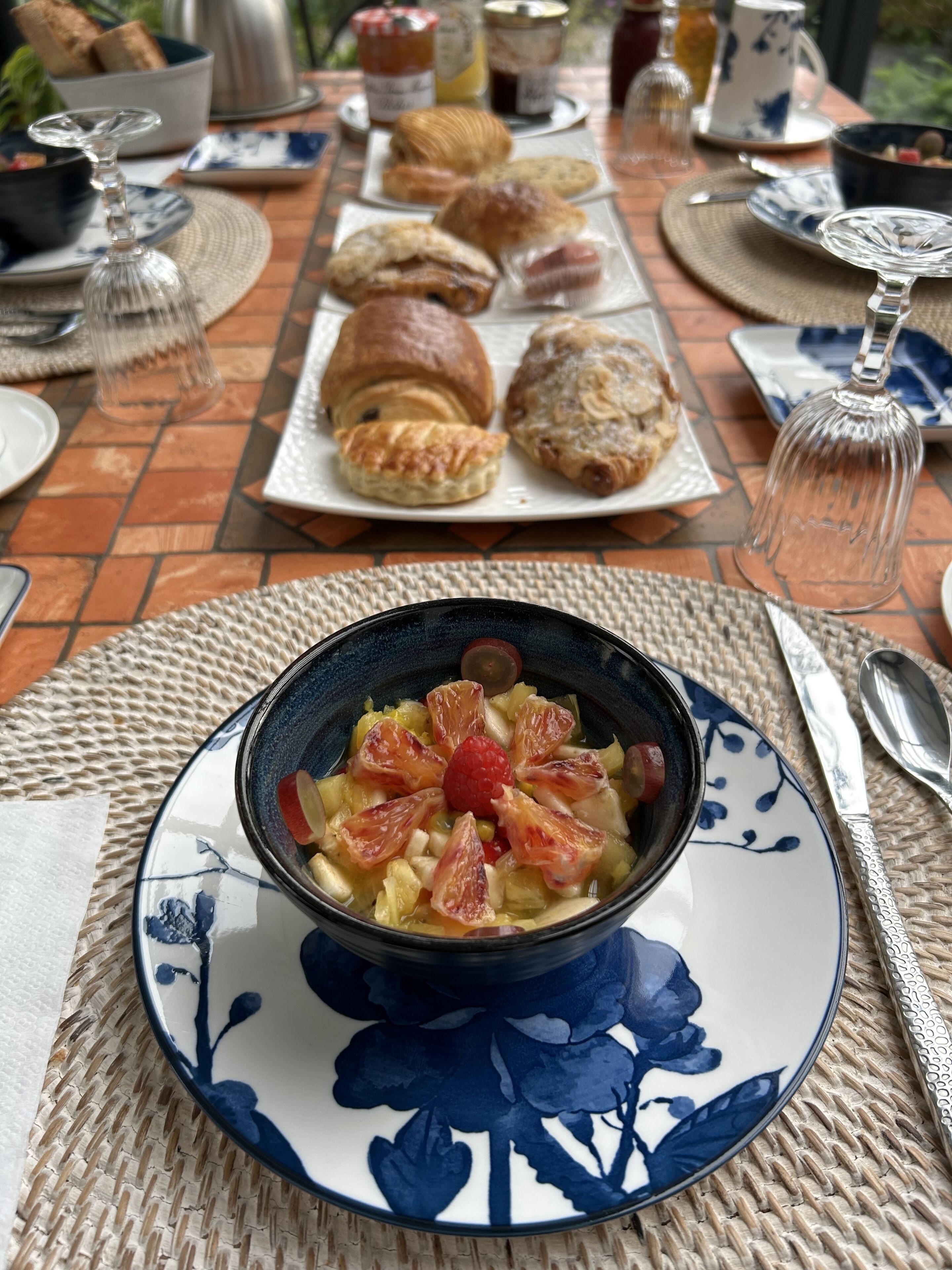 A table set with pastries, a bowl of fruit salad, and a teapot.