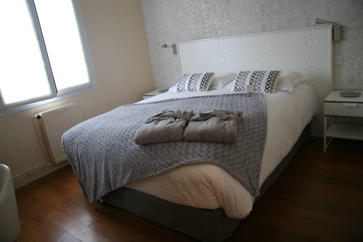 A bedroom with a bed, a nightstand, a chair, and a window.