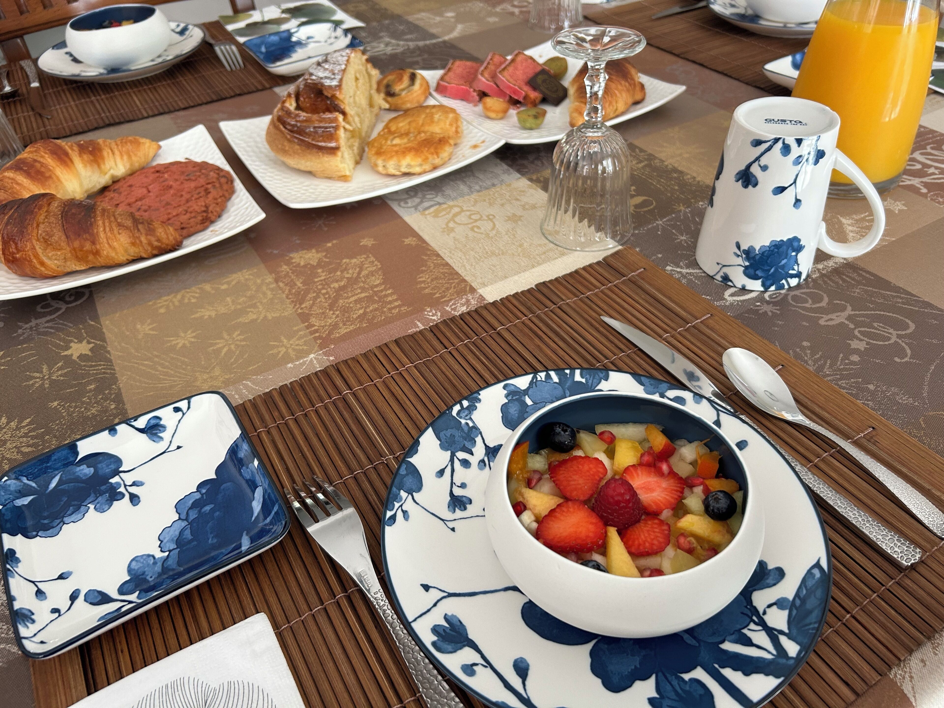 Ein Frühstückstisch mit Tellern voller Croissants, Gebäck und einer Obstschale.