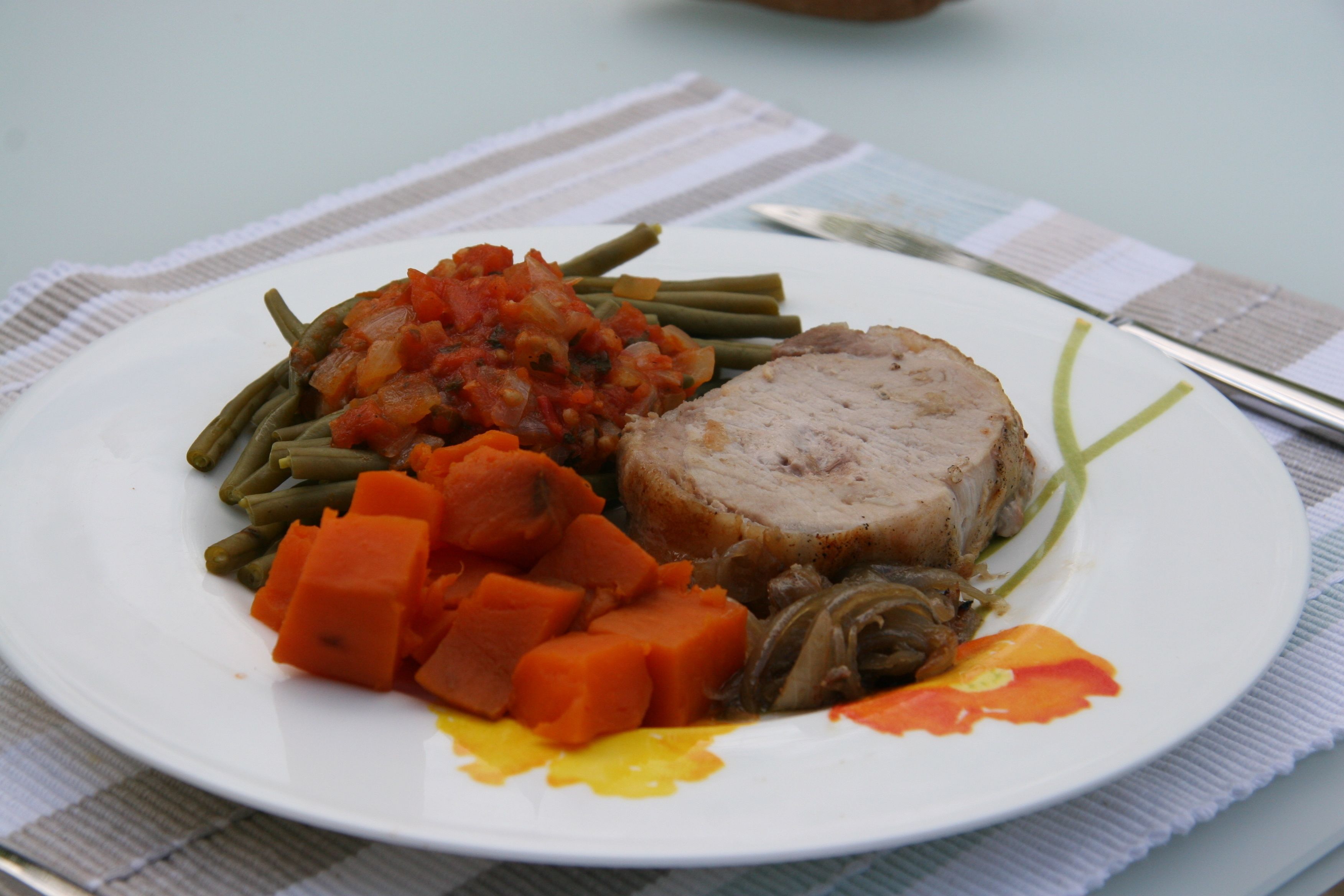 A plate with sliced meat, green beans, diced carrots, and a tomato-based sauce.