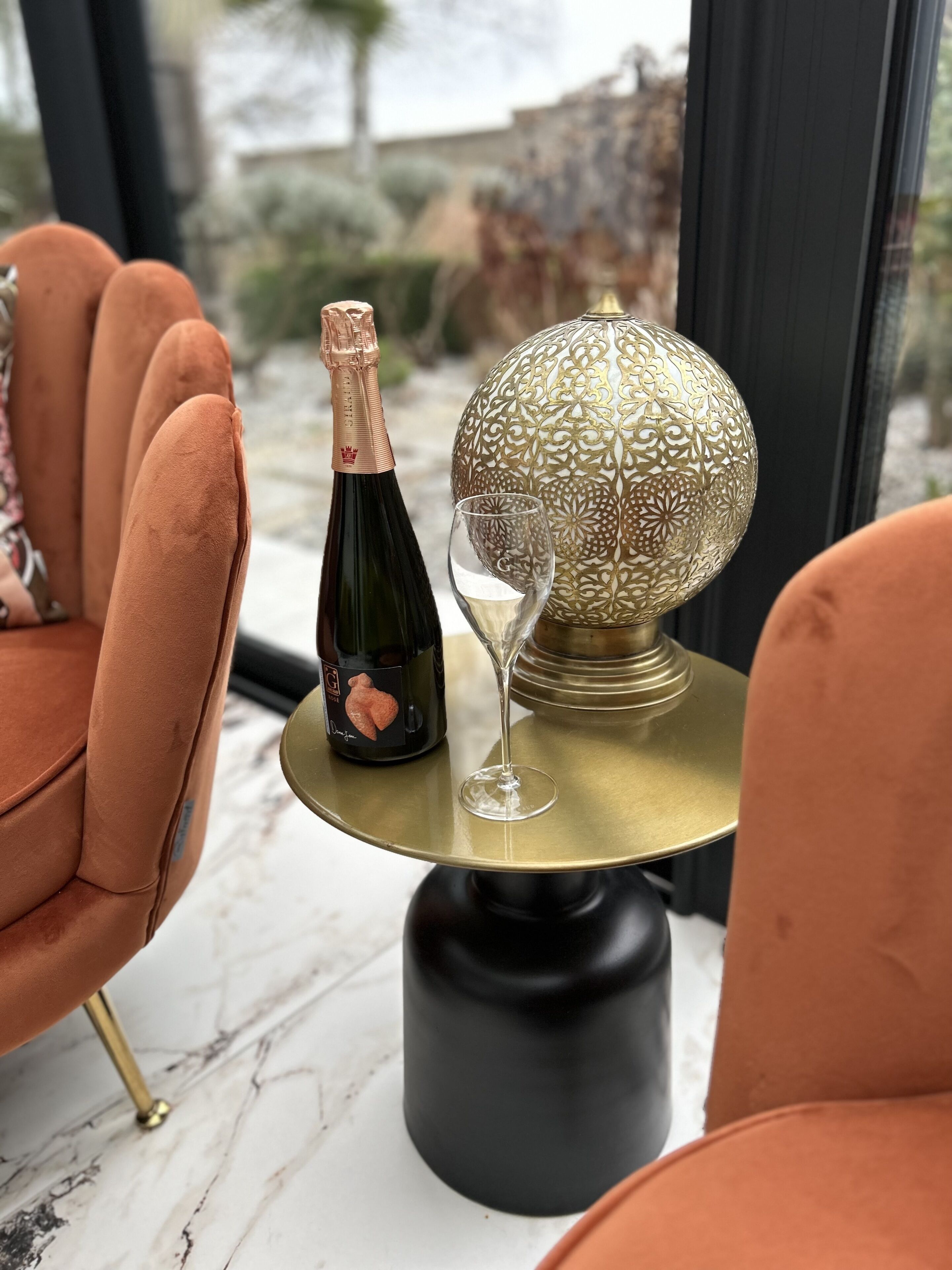 A table with a bottle of champagne, a glass, and a decorative globe.