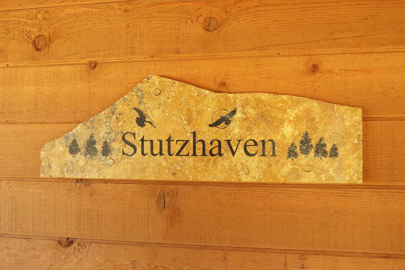 A wooden wall with a sign that reads "Stutzhaven" and features silhouettes of birds and trees.