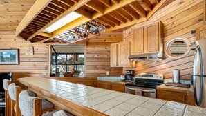 A wooden cabin-style kitchen with a large island, wooden cabinets, and a built-in oven. - Stutzhaven in the Mountains - 2 Br Home (Estes Park)