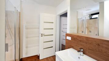 Un baño con cabina de ducha de vidrio, una bañera blanca y un tocador de madera.