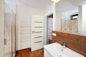 Un baño con cabina de ducha de vidrio, una bañera blanca y un tocador de madera.