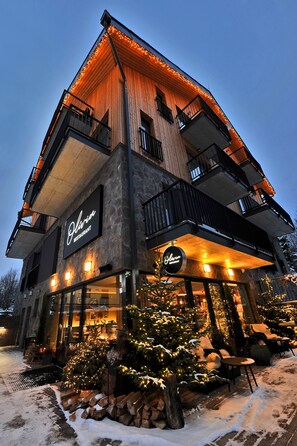 Een meerlaags gebouw met een bord voor een restaurant, terras en een met sneeuw bedekte grond.