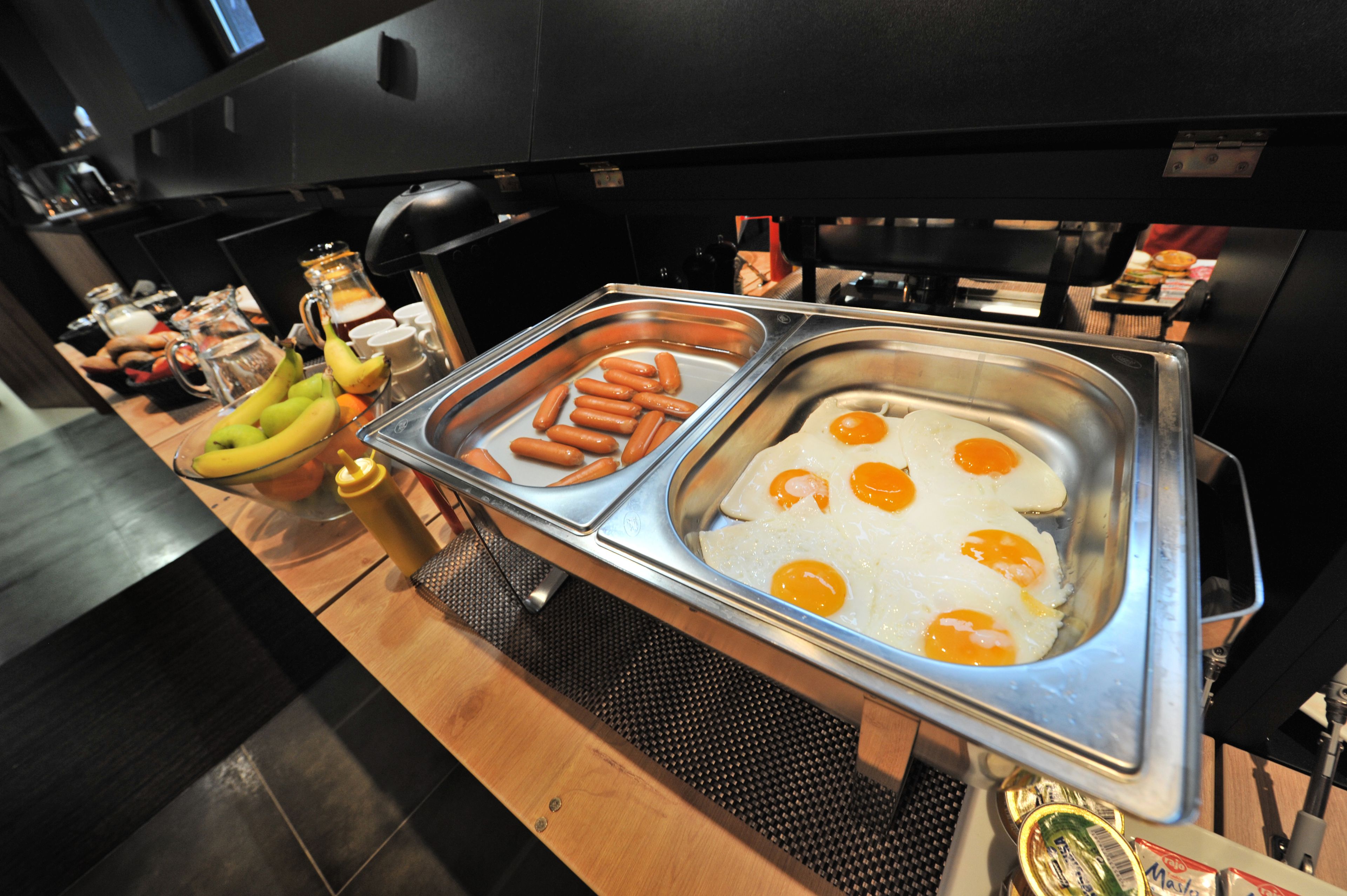 Een buffet met hotdogs, eieren en bananen.