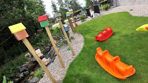 A well-maintained garden with wooden play structures and a small water feature. - APLEND Vila Olivia (Vysoké Tatry)