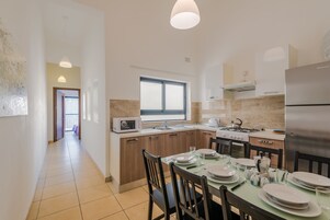 Una cocina moderna con comedor, que incluye una isla central, horno empotrado, microondas y refrigerador.