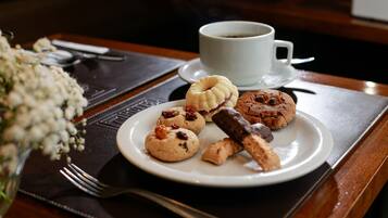 Taula de menjador amb un plat blanc d'assortiment de galetes i una tassa de cafè.