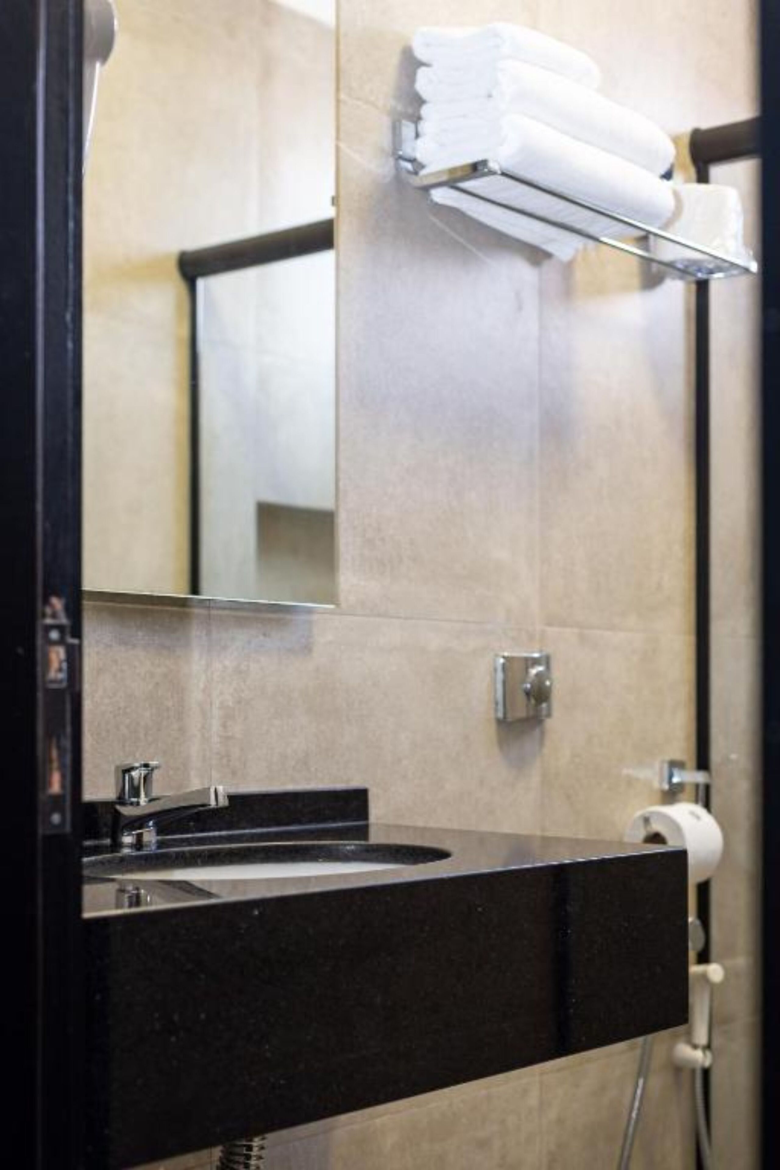 Ein modernes Badezimmer mit einem schwarzen Waschbecken, einem Spiegel und einem Handtuchhalter mit gefalteten Handtüchern.