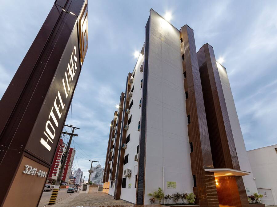 A modern hotel with a prominent sign, multiple floors, and a clear sky.