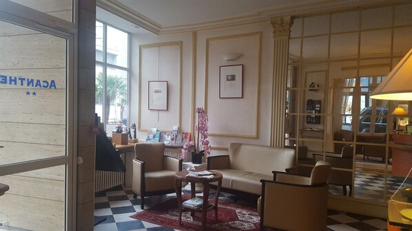 A hotel lobby with a checkered floor, a sofa, armchairs, a coffee table, and a potted orchid. - ACANTHE HOTEL (Bordeaux)