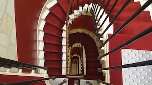 A spiral staircase with red and white walls, metal handrails, and a central landing area. - ACANTHE HOTEL (Bordeaux)