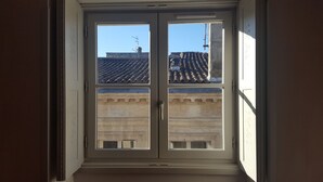 A window with a view of a building with a tiled roof and a stone facade. - ACANTHE HOTEL (Bordeaux)
