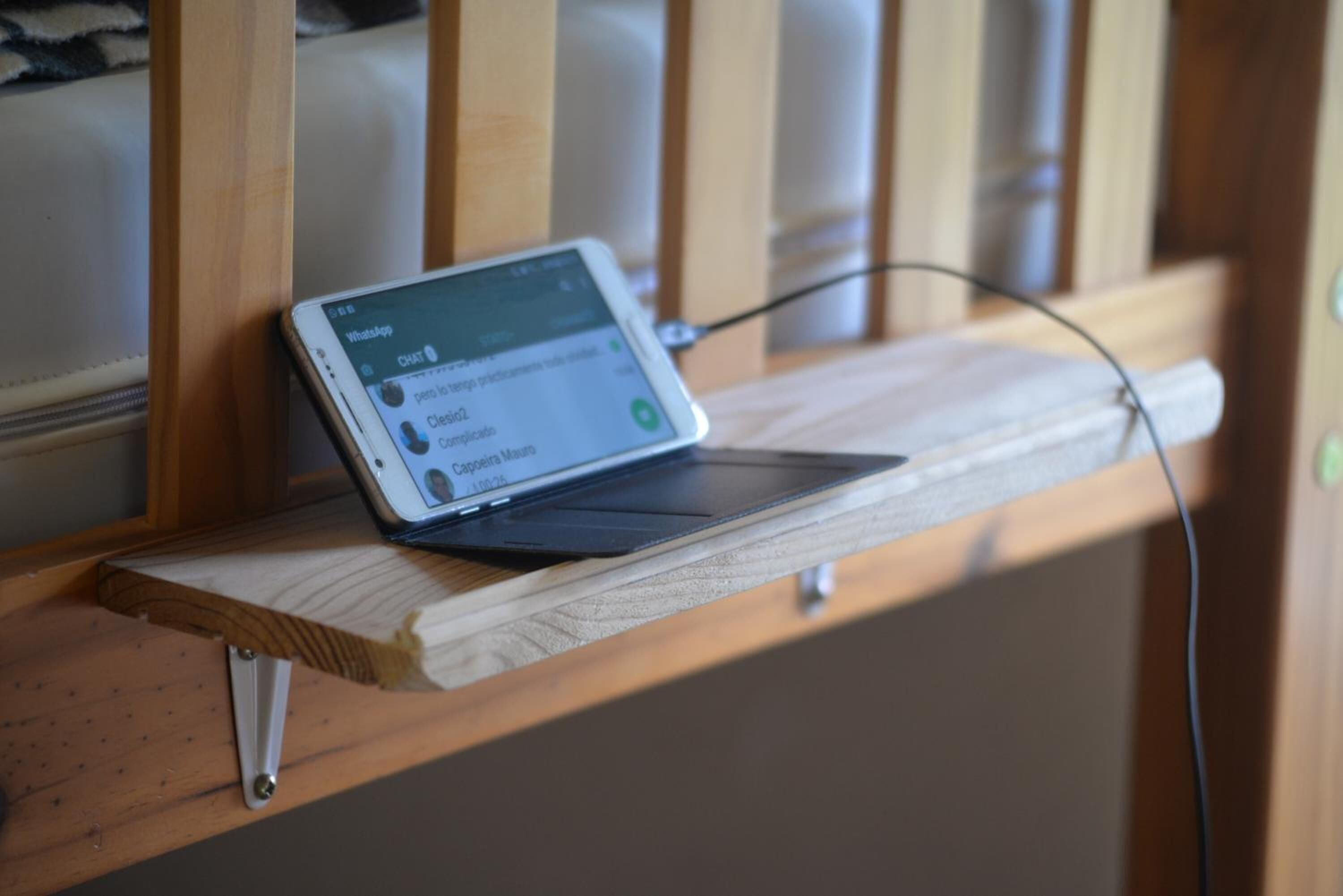Un téléphone intelligent posé sur une étagère en bois, avec une rambarde en bois en arrière-plan.