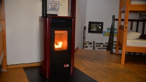 A wood-burning stove with a fire burning inside, a bunk bed with a number 5, and a sign that says "DON'T TOUCH NO TOCAR PLEASE". - Albergue A Casiña di Marcello - Hostel (Palas de Rei)