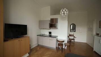 Ein gemütlicher Wohnbereich mit Küchenzeile, Essplatz und Fernseher.