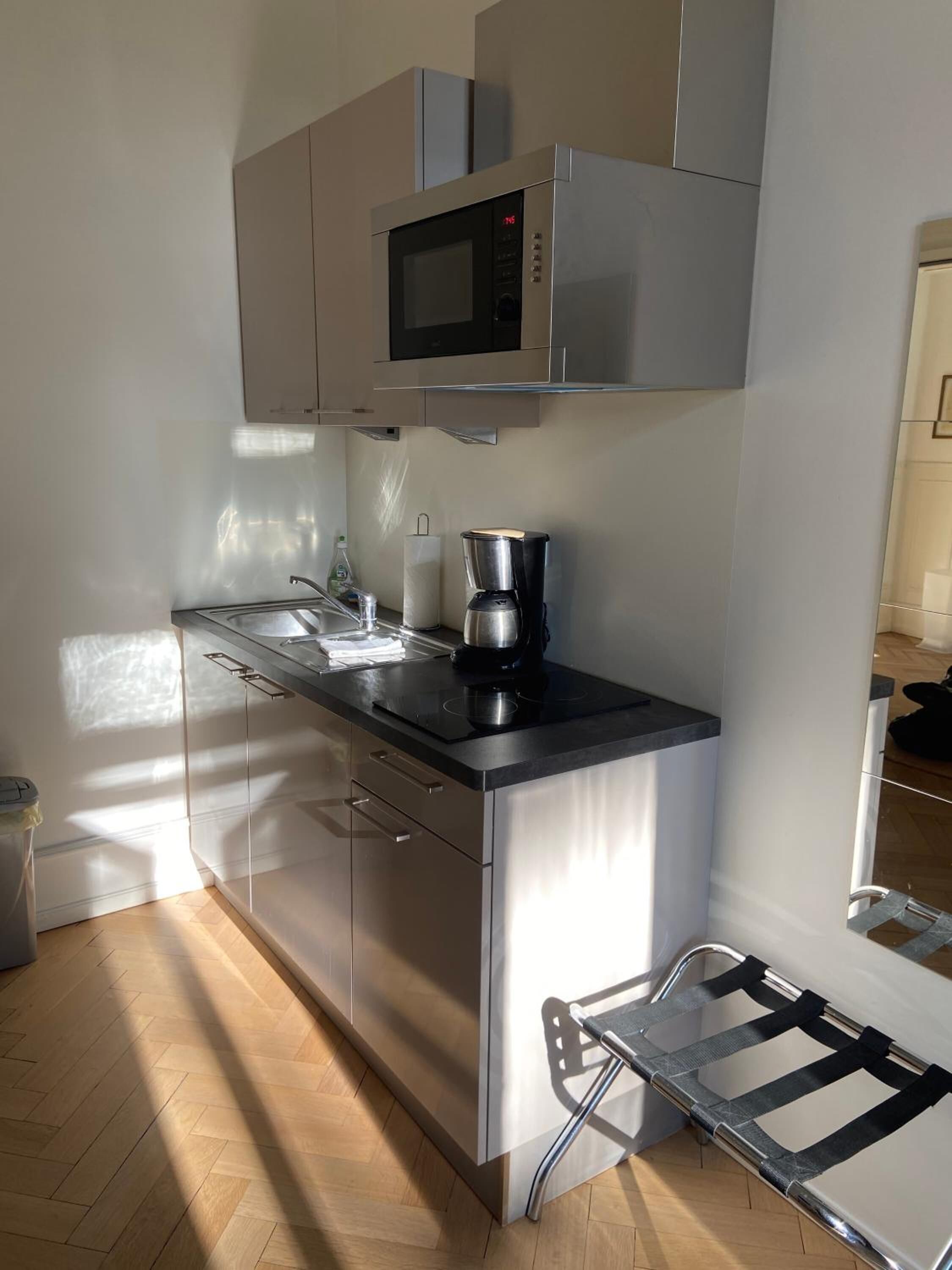 Eine moderne Küche mit Edelstahlgeräten, einer Kaffeemaschine und einem eingebauten Backofen.