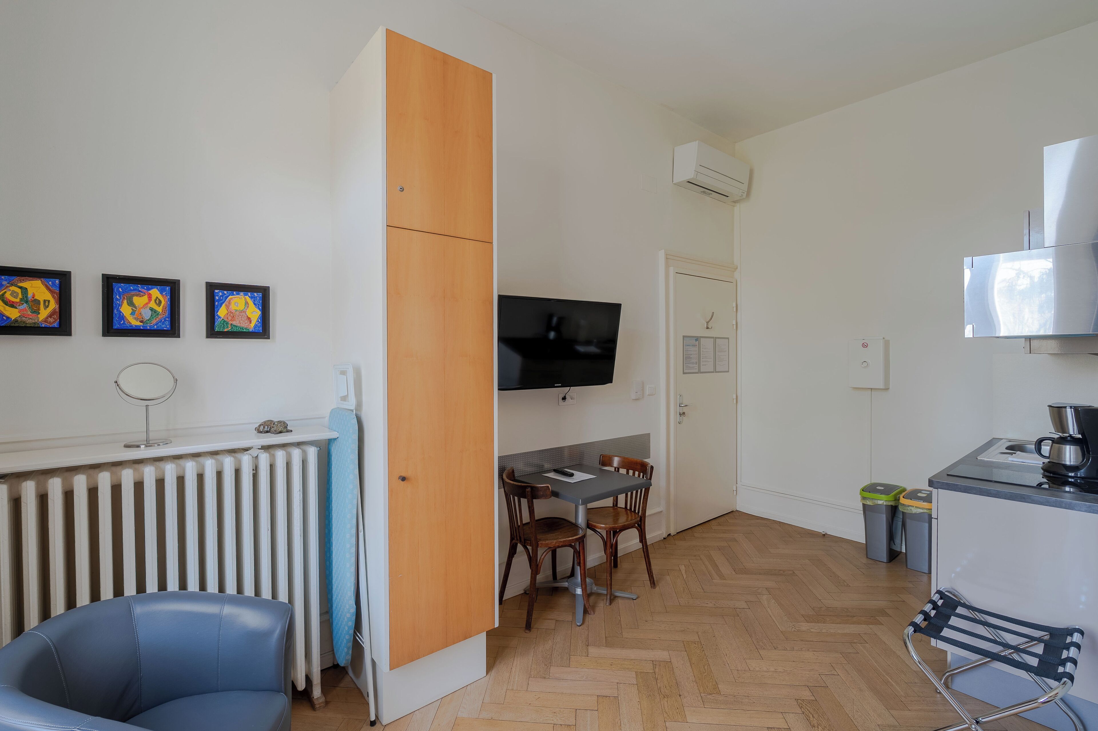 Une cuisine de taille réduite avec un coin repas, un téléviseur fixé au mur et un radiateur.