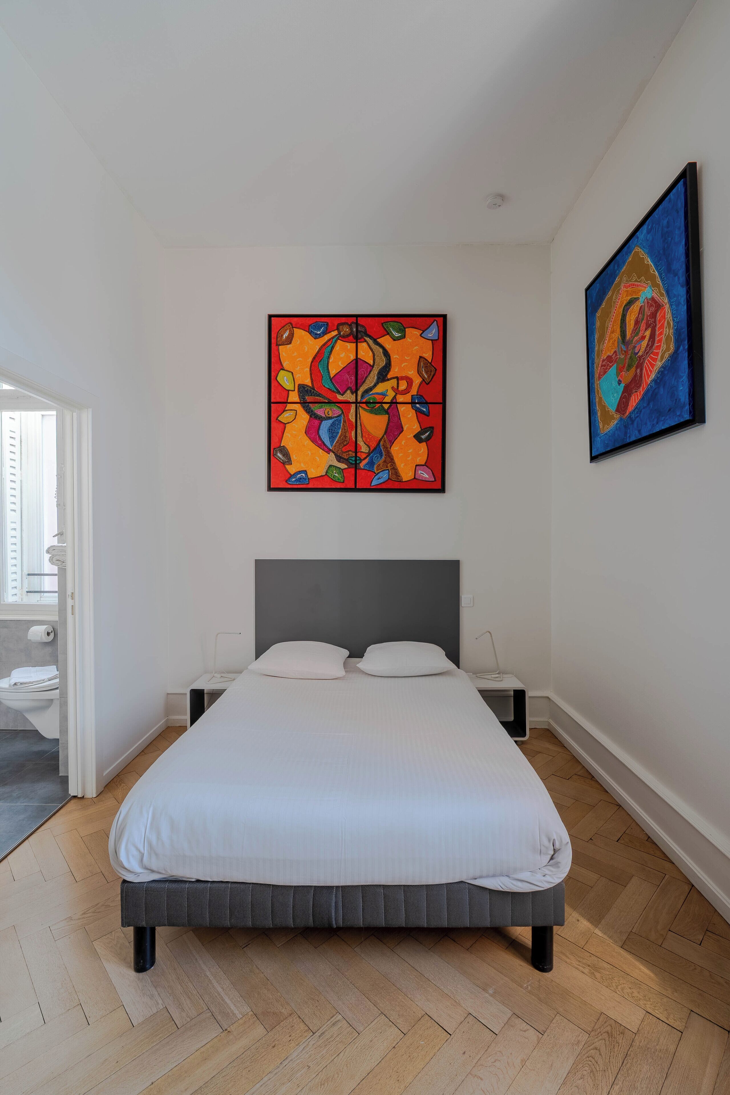 Ein modernes Schlafzimmer mit einem Bett, zwei Nachttischen und zwei an der Wand hängenden Bildern.