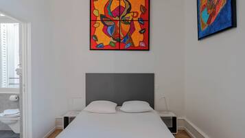 Ein modernes Schlafzimmer mit einem Bett, zwei Nachttischen und zwei an der Wand hängenden Bildern.