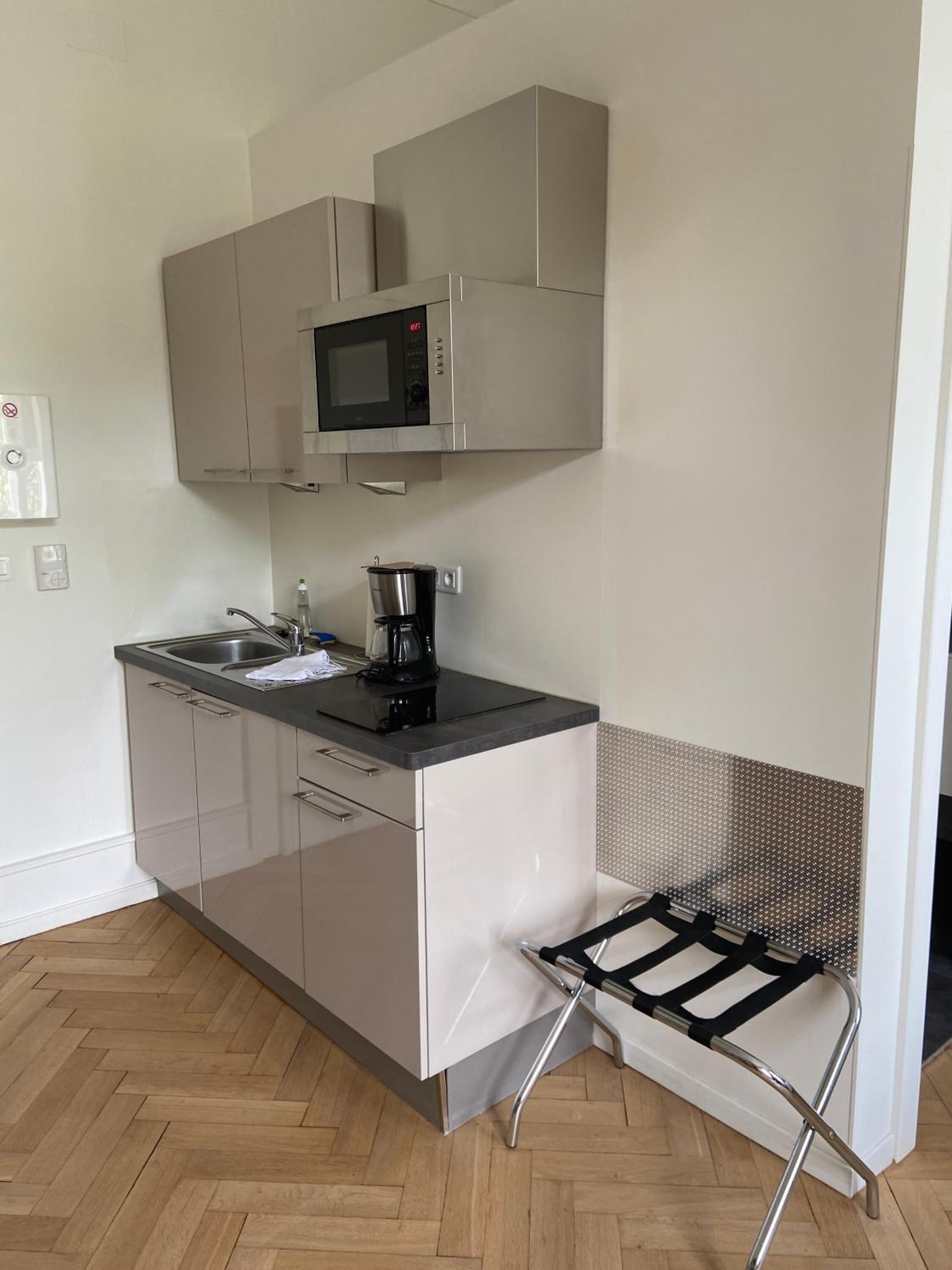 A compact kitchen with a microwave, coffee maker, and a small sink.