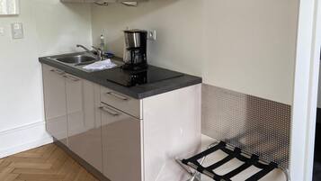 A compact kitchen with a microwave, coffee maker, and a small sink.