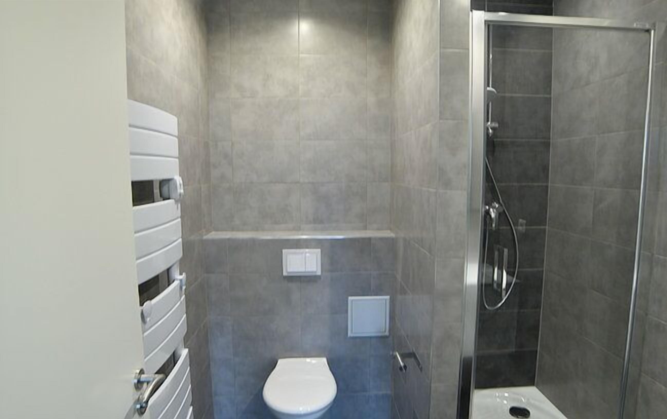 Une salle de bain moderne équipée de toilettes, d’une douche et d’un porte-serviettes.