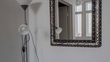 A room with a large mirror, a floor lamp, and a chair.