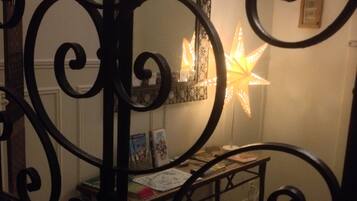 Quarto com luminária em formato de estrela, uma pequena mesa com livros e um guarda-corpo metálico decorativo.