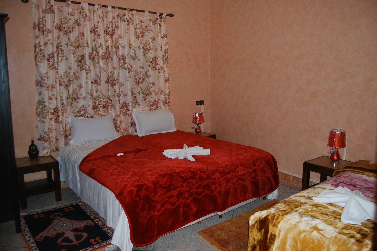A hotel room with a bed, a nightstand, a lamp, and a small table.