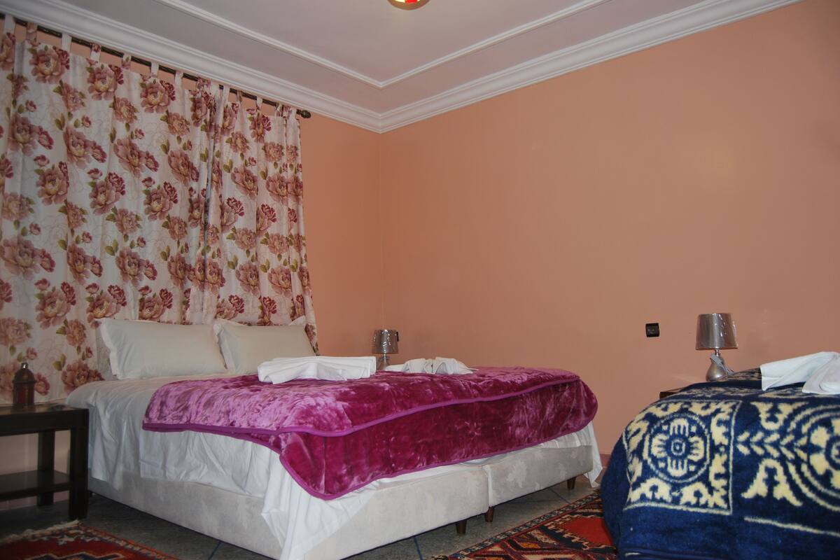 A bedroom with a bed, a nightstand, a lamp, and a patterned rug.