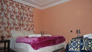 A bedroom with a bed, a nightstand, a lamp, and a patterned rug.