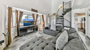 A spacious living room with a large flat-screen TV, grey sofas, a wooden coffee table, and a staircase leading to an upper floor. - Mv17 amazing lake view  spacious ski cabin (Stateline)