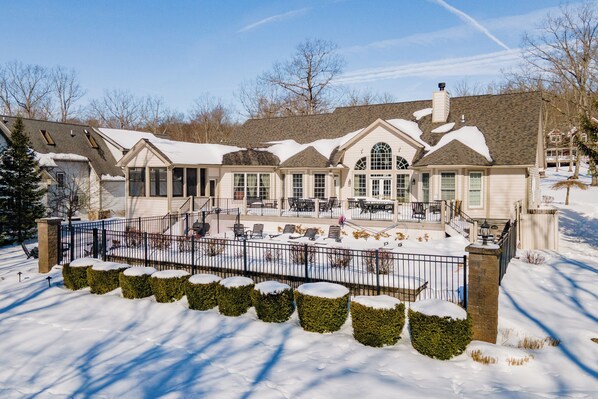 A large, two-story house with a covered patio area and a fenced backyard. - Signature Lakefront w/ Dock & Outdoor Pool (SWANTON)
