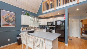A modern kitchen with a large island, white cabinets, and a wooden ceiling. - Swiss-Style Dog Friendly Chalet w/ Hot Tub (SWANTON)
