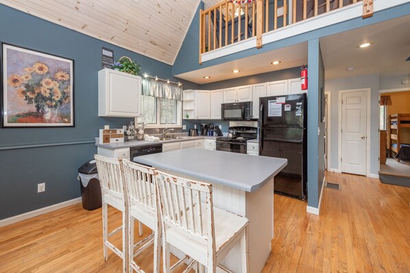 A modern kitchen with a large island, white cabinets, and a wooden ceiling. - Swiss-Style Dog Friendly Chalet w/ Hot Tub (SWANTON)