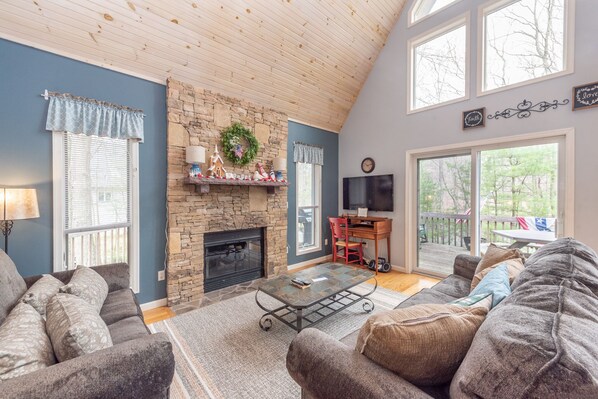 A cozy living room with a stone fireplace, a television, and a comfortable seating area. - Swiss-Style Dog Friendly Chalet w/ Hot Tub (SWANTON)