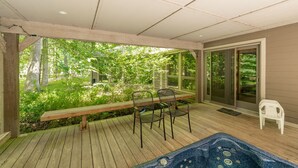 Eine Holterrasse mit Whirlpool, Stühlen und einer Bank.